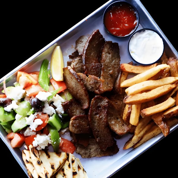 Twisted Greek gyro platter with sliced meat, fries, Greek salad, pita bread, and dipping sauces.